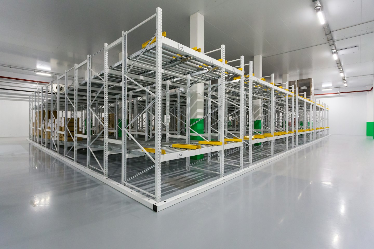 Interno di un moderno magazzino con scaffalature a pallet bianche e accenti gialli.
